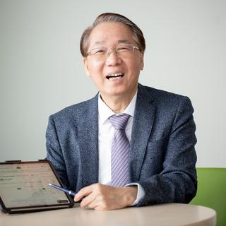 A man in a suit pointing at a tablet and laughing
